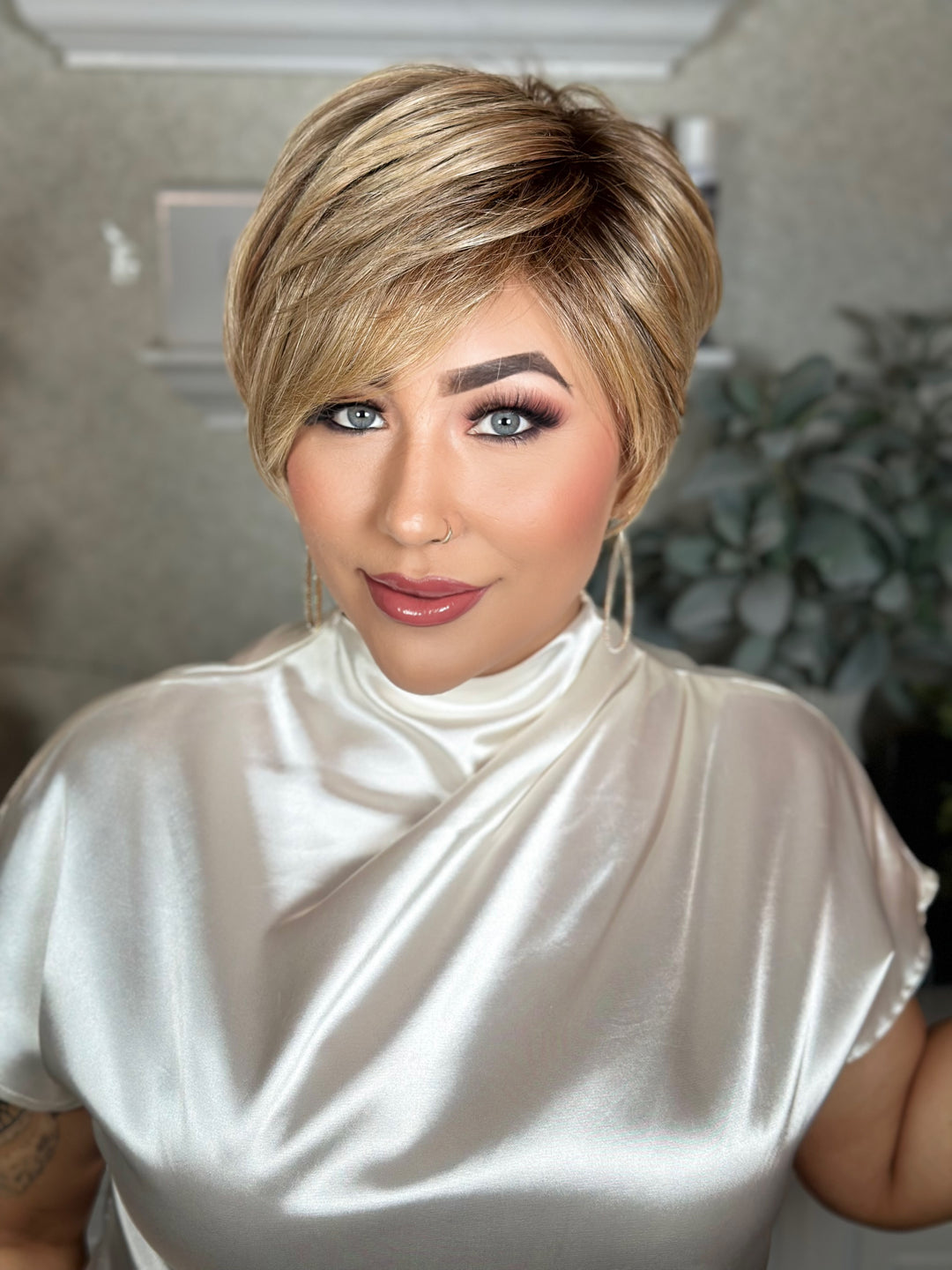 Woman with a stylish haircut wearing a white top indoors.