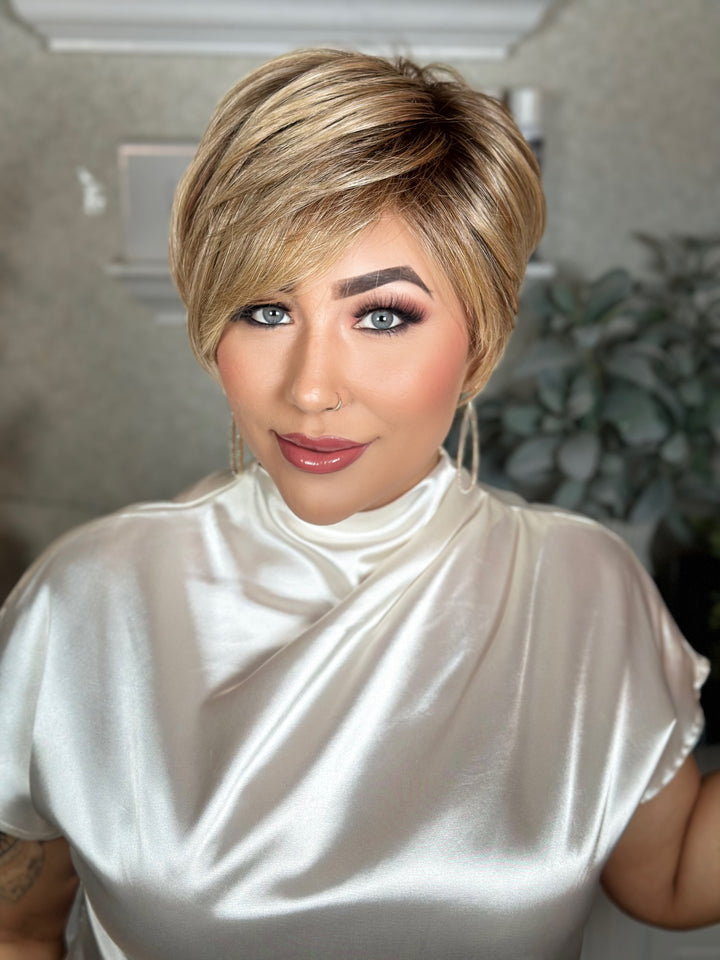 Woman with a stylish haircut wearing a white top indoors.