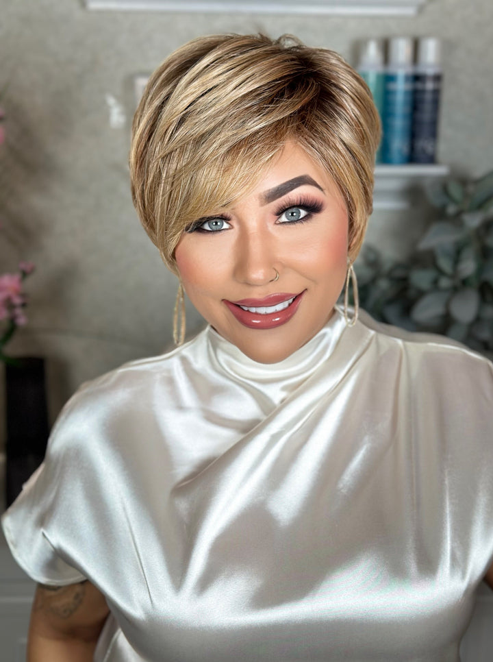 Woman with a stylish haircut wearing a white top in an indoor setting.